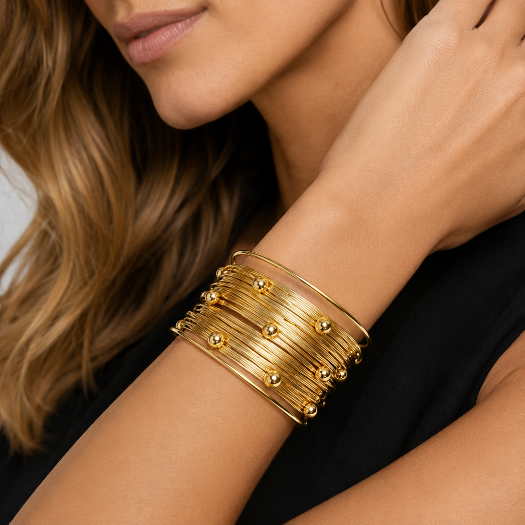 Close up detail of a layered gold wire statement cuff with delicate gold bead accents on a woman's wrist