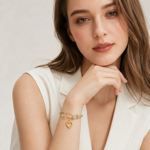 Model in a crisp white vest styling a dainty double-chain gemstone heart bracelet