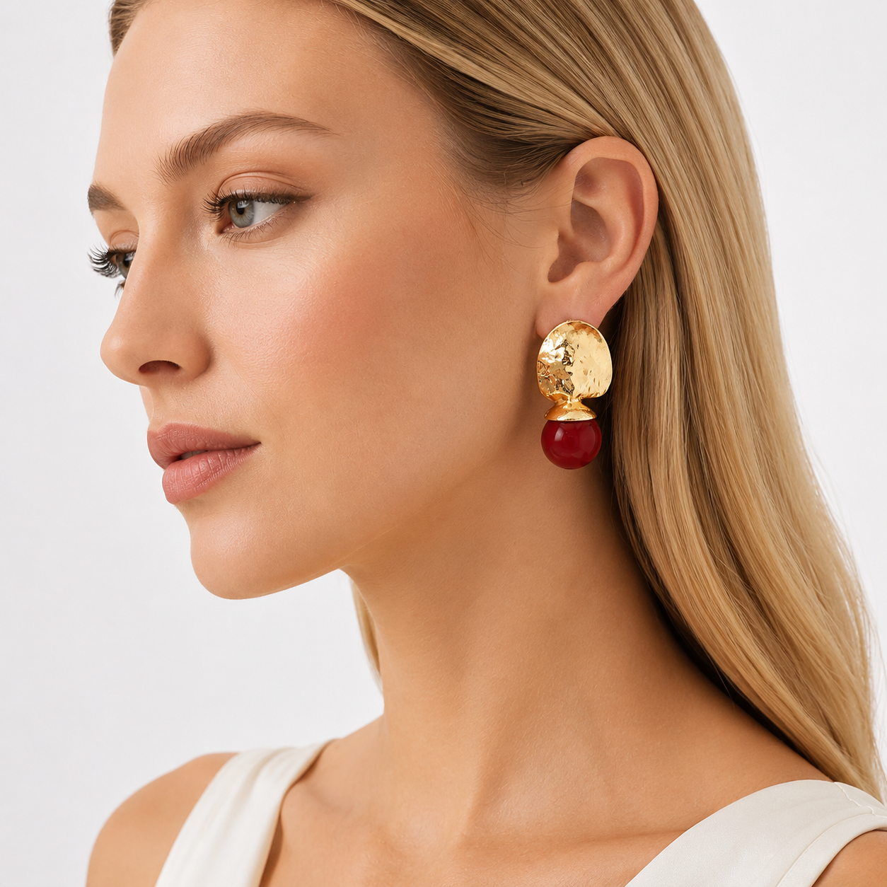 Side view of woman wearing gold red drop earrings