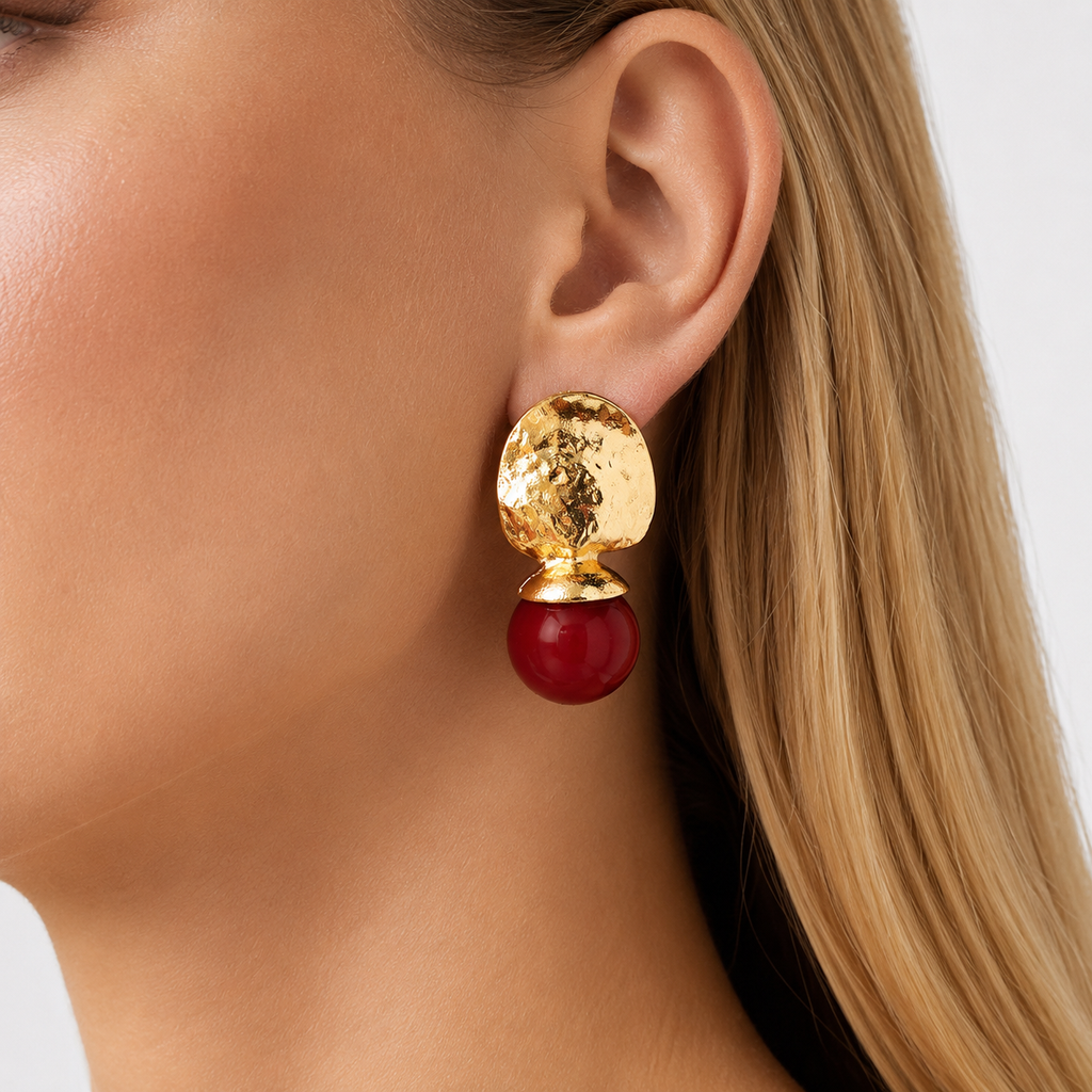 Close up of gold red drop earring with hammered metal texture