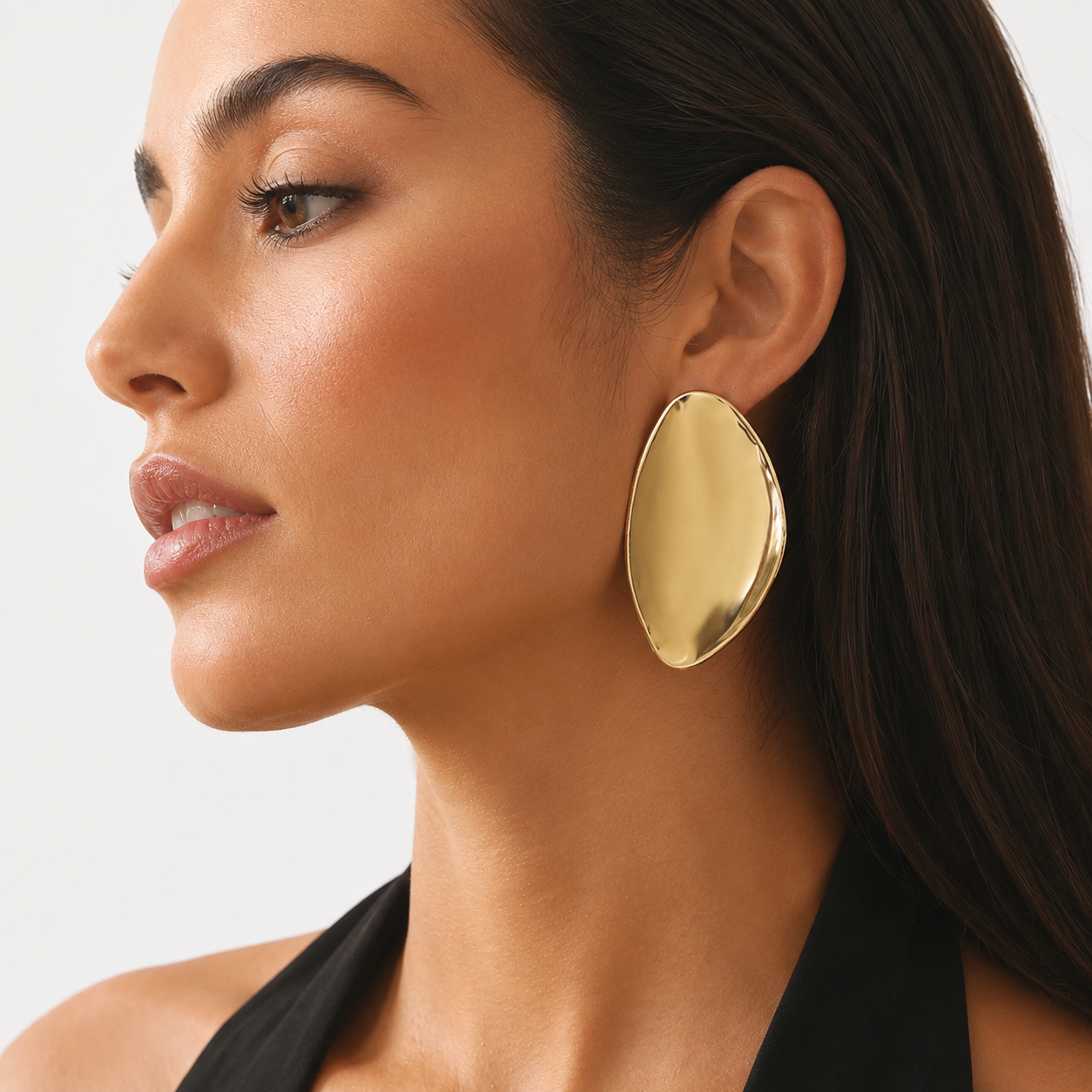 Side profile of woman wearing a large high-polish organic gold statement earring
