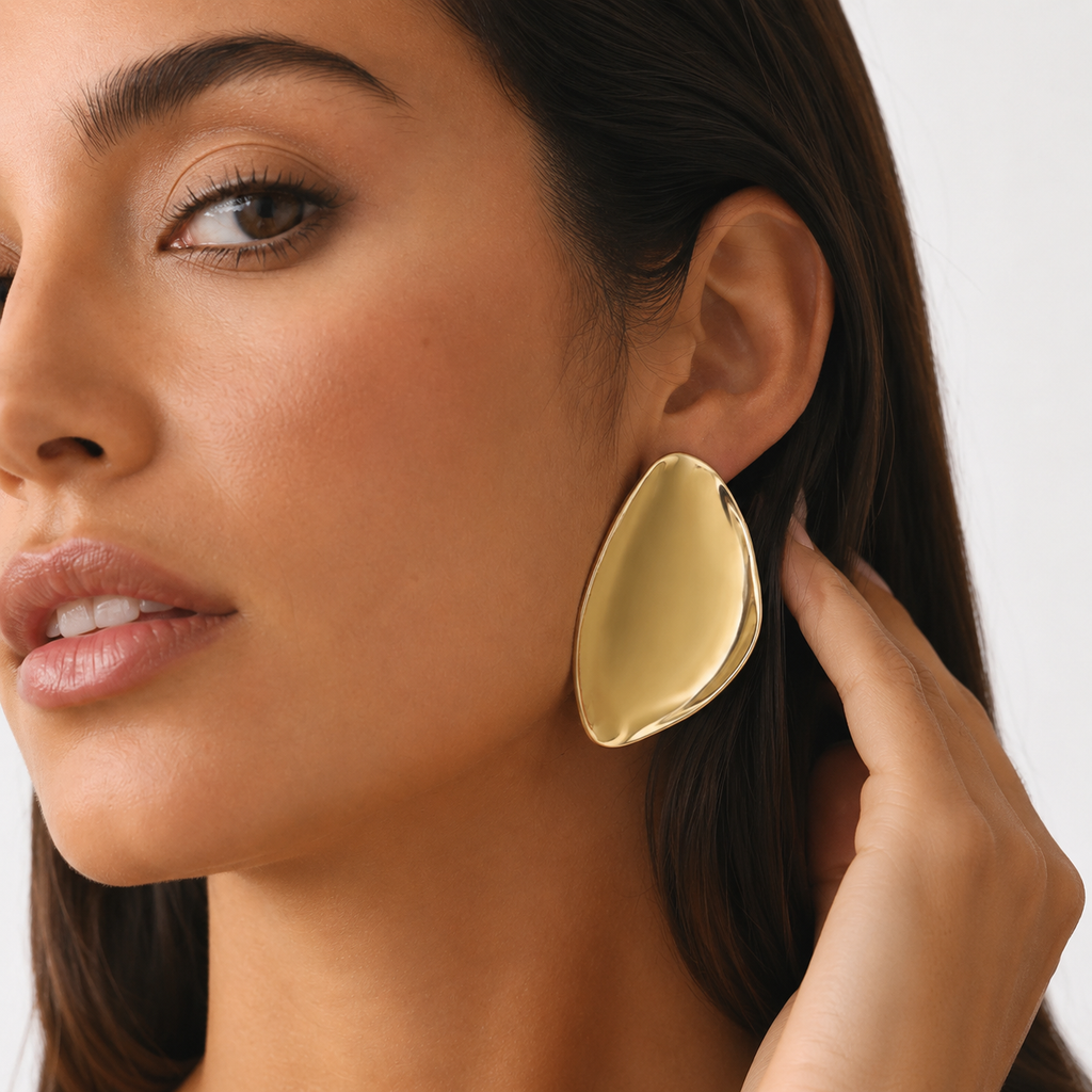 Close-up of model tucking hair behind ear, showcasing a chunky modern liquid gold earring