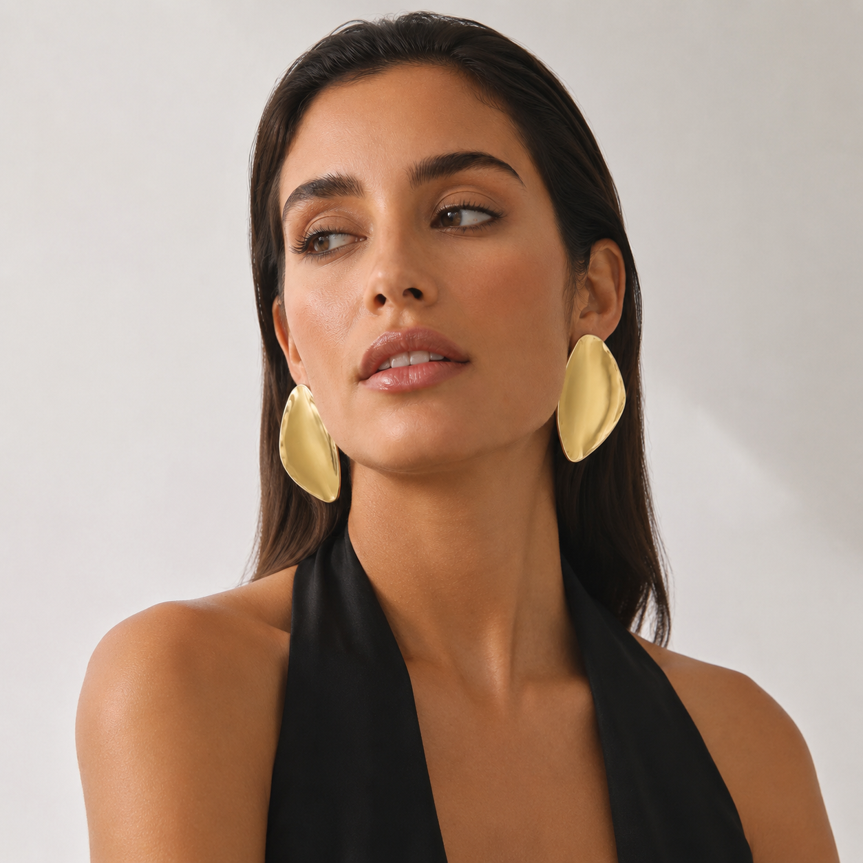 Model looking away, displaying the striking scale of avant-garde gold sculptural earrings