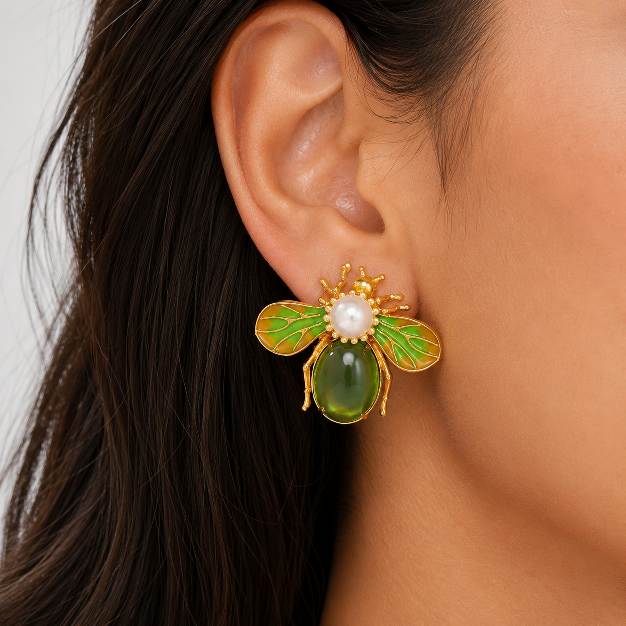 Close up of green bee earrings with pearl accent